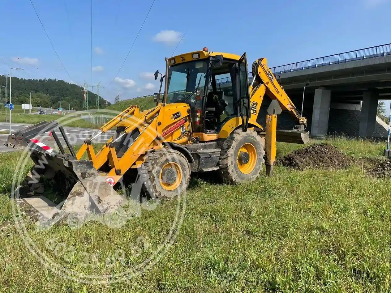 Traktor-bagr JCB při výkopových pracích na usazení kanalizačních skruží u dálnice ve Frýdku-Místku